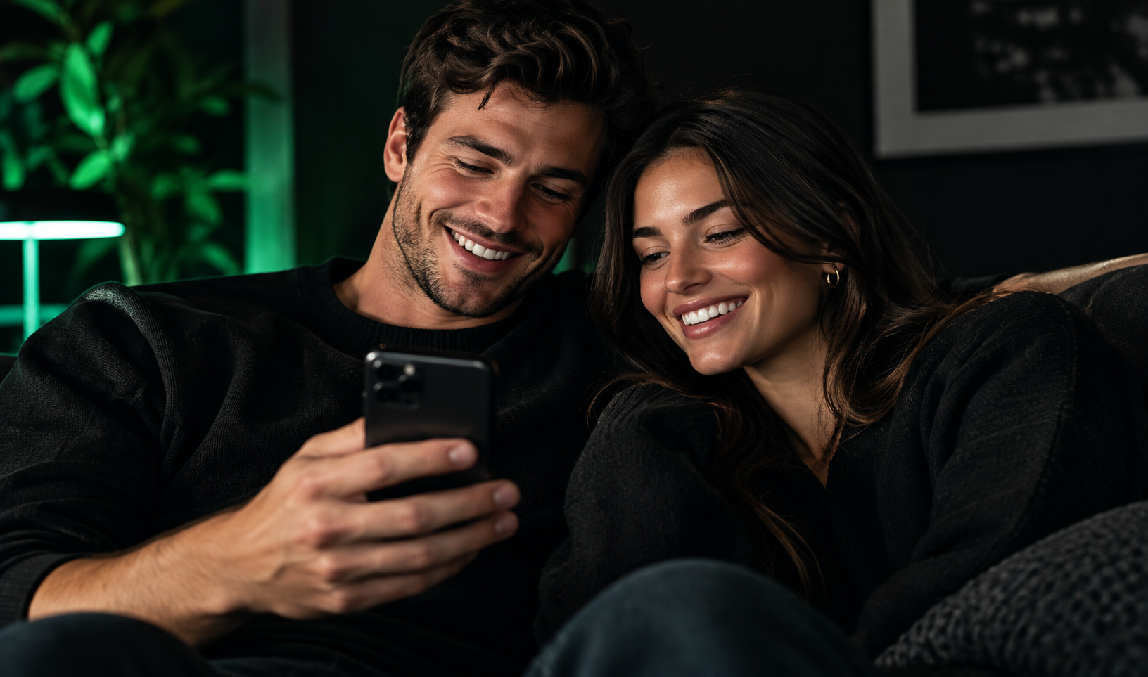 A couple on the couch looking at their shared plan on one phone